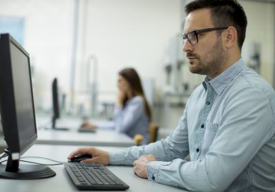 Side view of focused students using desktop pc in classroom